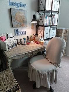 a desk with a chair, lamp and pictures on the wall above it in a bedroom