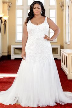 a woman in a white wedding dress standing on a red carpet with her hands on her hips