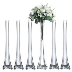 four tall vases with flowers in them on a white background, one is empty