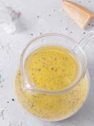 a glass bowl filled with yellow liquid next to a piece of bread