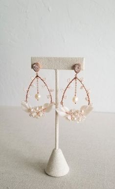 a pair of earrings with pearls and crystal beads on a white display stand in front of a wall