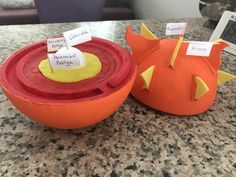 two orange bowls sitting on top of a counter next to each other with signs in them