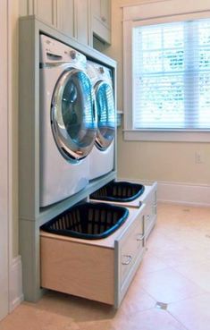 a washer and dryer in a room with tile flooring, white walls and cabinets