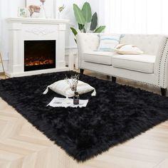 a living room with white furniture and a black rug in front of a fire place