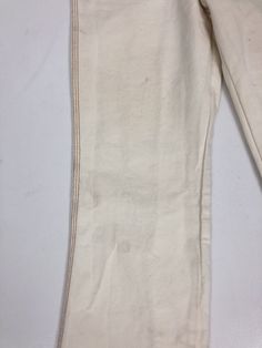 "1970's white denim Wrangler flares have contrast rust colored topstitching throughout, hip pockets, back patch pockets with curvy top stitching, and a zip fly with a metal stud button closure at the waist. Condition Excellent overall. Has some discolored spots on both front legs, and near the back hem. Theres a little bit of green discoloration on back metal rivets. Measurements Waist 26\" Hip 30\" Rise 10\" Inseam 31\" Length 40\"" Spring Flare Jeans With Contrast Stitching, White Straight Leg Jeans With Contrast Stitching, Fitted Cream Cotton Jeans, Cream Cotton Flare Jeans, Cream Cotton Flare Jeans For Fall, Retro White Straight Leg Jeans, White Cotton Bottoms With Contrast Stitching, Vintage White Straight Leg Pants, M Photos