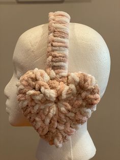 a white mannequin's head is adorned with pink and beige yarns