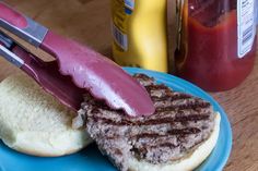 a hamburger being cut with a knife on a plate next to some condiments