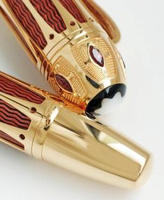 two gold and red fountain pens sitting on top of each other