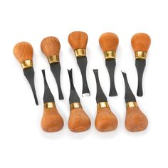 six wooden brushes with black handles and gold tips