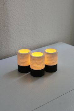 three lit candles sitting on top of a white table