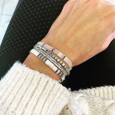 a close up of a person's arm wearing two bracelets and a sweater