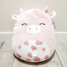 a pink and white cow shaped pillow with hearts on it's face sitting on the floor