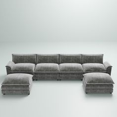 a large sectional couch sitting on top of a white floor next to a footstool