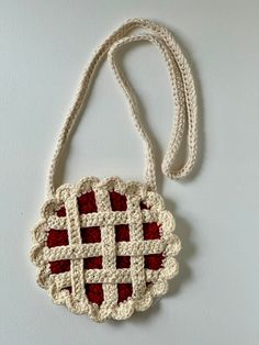 a crocheted bag hanging on a wall with a white cord attached to it