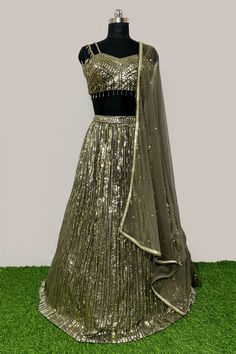 Description: - Blouse is based on net fabric and is designed in a sweetheart neckline with sleeveless with sequins and cut dana all over. Back is sheer net.The Shimmery lehenga skirt on Georgette has vertical shimmer lines and is completed with soft net attached dupatta in complementing color. Garment is chic and sophisticated. Color Golden & Mehandi Green Fabric Georgette, Net Occasion Party Wear Wedding Wear Style Lehenga Choli Work Embroidery Chest Size 38 Lehenga Length 45 Please note: Origi