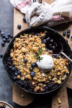 blueberry cobbler in a cast iron skillet topped with ice cream and crumbs