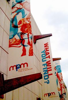 a tall building with many different posters on it's side and the sky in the background