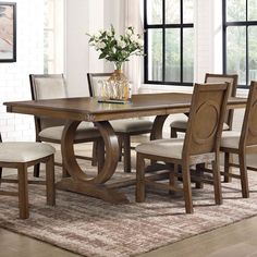 a dining room table with chairs and a vase filled with flowers on top of it