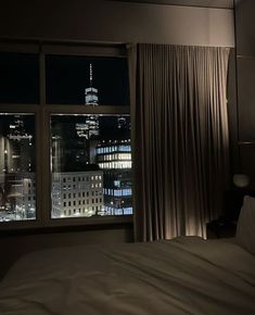 a bed sitting next to a window in a bedroom under a night time sky line