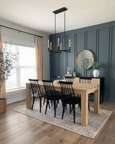 a dining room with blue walls and wooden flooring, black chairs and a table