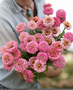 a woman holding a bunch of pink flowers