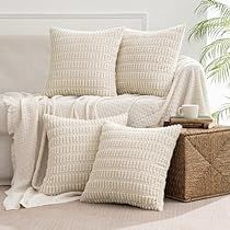 a white couch with pillows on top of it next to a basket and potted plant