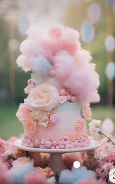 a pink and white cake with flowers on top is surrounded by cotton bounches