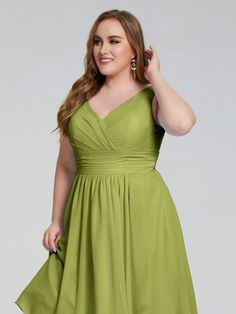 a woman in a green dress with her hands on her hip, posing for the camera