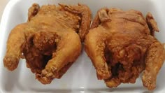 two pieces of fried chicken sitting on top of a white plate in a plastic container