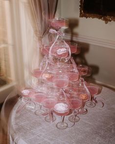 a table topped with lots of wine glasses on top of a white cloth covered table