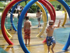 two young boys playing in a water park with colorful rings around them and people watching