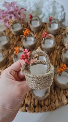 a person holding up some rope with flowers on it in front of other items and candles