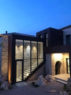 a modern house lit up at night with stone steps leading to the upper floor and second story