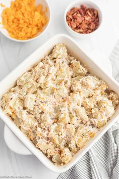 a casserole dish with cheese, nuts and other ingredients in bowls on the side