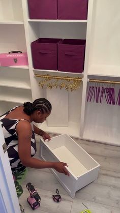 a woman is opening a shoe box on the floor in front of some closets