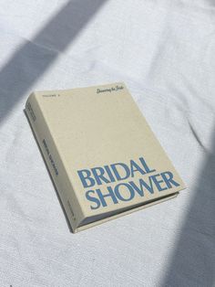 a book sitting on top of a white cloth covered tablecloth with the title bridal shower written in blue