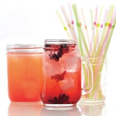 three mason jars filled with different types of drinks and drinking straws on the table