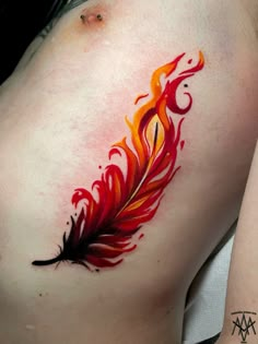 a woman's stomach with a red and orange feather tattoo on the side of her belly