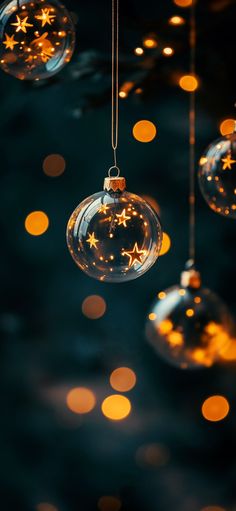 christmas ornaments hanging from strings with lights in the background