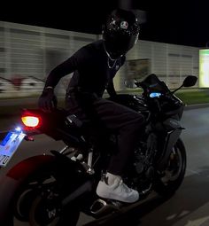 a man riding on the back of a motorcycle at night