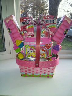 a pink basket filled with candy and candies on top of a table next to a window