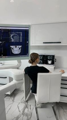 a woman sitting at a desk in front of a computer monitor with drawings on it