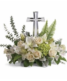 a cross with flowers and greenery in it