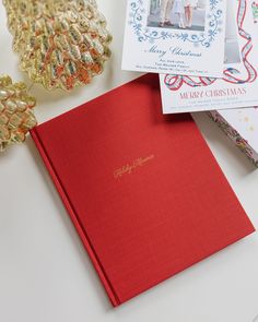 a red book sitting on top of a white table next to other christmas cards and decorations