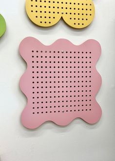 three pieces of plastic with holes on them are hanging on the wall next to each other