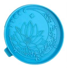 a blue plate with a flower and moon design on the front, sitting on a white surface