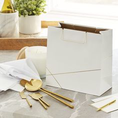 a white bag sitting on top of a counter next to gold utensils