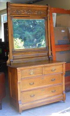 an old dresser with a large mirror on it's top and bottom drawer open