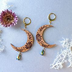 These botanical crescent moon earrings are an everyday accessory that will add a simple and dreamy touch to your look. These original earrings feature an etched cherry wood crescent moon with succulents, vines, and stars. At the base of the moon hangs a black Czech glass teardrop bead with an iridescent iris finish of purple, green, and blue. Lightweight and whimsical, these moons will go with everything and make a wonderful gift for a loved one. Option 1: Silver Ear WiresThis option features hypoallergenic silver 304 stainless steel ear wires. Option 2: Gold Ear WiresThis option features hypoallergenic gold 304 stainless steel ear wires. Option 3: Gold LeverbacksHypoallergenic gold 304 stainless steel round leverback ear hooks. Crescent Moon Earrings, Teardrop Beads, Everyday Accessories, Moon Earrings, Cherry Wood, Green And Blue, Purple Green, Crescent Moon, Earring Necklace