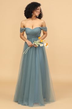 a woman in a blue dress is standing with her hands on her hips and looking off to the side